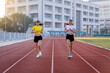 © EduLife Photos - Two young Asian women in sports outfits jogging on running track in city stadium in the sunny morning to keep fitness and healthy lifestyle. Young fitness women run on the stadium track