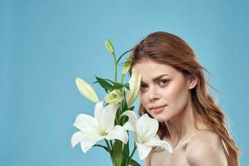 Woman with a bouquet of white flowers on a blue background naked shoulders beautiful face