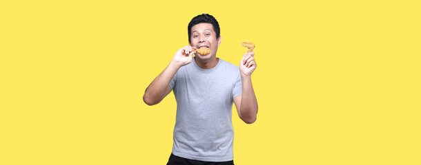 Asian man is eating fried chicken deliciously on Yellow background