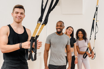 Wall Mural - Multiethnic fitness team doing stretching exercise with suspension band