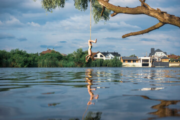 The boy hangs on a rope with his head to the water. Bungee jumping into the water