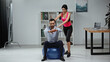 © LIGHTFIELD STUDIOS - Fitness trainer standing near businessman on fitness ball in office