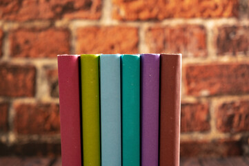 Poster - Stack of books in the library room lay on the wood table with brick backround.