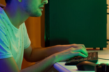 Wall Mural - Closeup shot of a man typing on a keyboard sitting in front of a computer