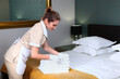 © Alla - Change of towels in the hotel room. A uniformed maid cleans the room. Towels in the hands of the maid. The concept of the hotel business. A bed in the interior of a hotel room.