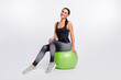 © deagreez - Full length photo of happy young woman sit fit ball good mood pilates isolated on grey color background