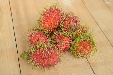 Red rambutan fruit on wood plank.