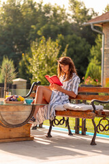 Woman reading a book outdoors on sunny summer morning