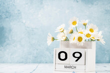 White Cube Calendar For March Decorated With Daisy Flowers Over Blue With Copy Space