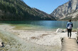 © Chris - A woman walking along the shore of Leopoldsteiner lake in Austria. The lake is surrounded by high Alps. The shallow water is crystal clear, spring water has a calm surface. Early spring. Serenity