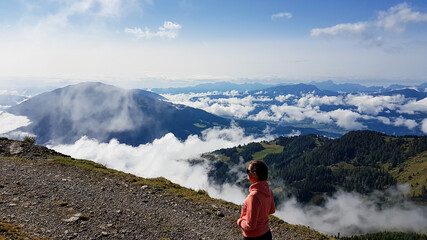 a woman hiking along a gravelled road and enjoying the idyllic view on alpine valley from the top of