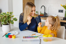 Mother And Daughter Painting At Home. Cute Little Kid In Yellow Sweater Having Fun With Parent And Paints. Concept Of Early Childhood Education, Hobby, Talent, Preschool Leisure And Parenting