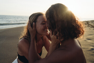 The couple in love touches each other's noses and smile with happiness against the backdrop of sand and ocean. High quality photo