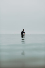 Young Female Surfer Sitting On Surfboard In Calm Misty Sea, Ventura, California, USA
