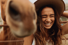 Young Woman In Felt Hat Laughing Next To Horse, Jalama, California, USA