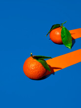 Two Oranges On Vivid Blue Background With Trailing Orange Stripes