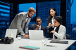 © Connect Images - Businesswomen and men looking at laptop during conference table meeting