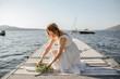 © Connect Images - Young bride in wedding dress laying bouquet on lake pier, Stresa, Piemonte, Italy