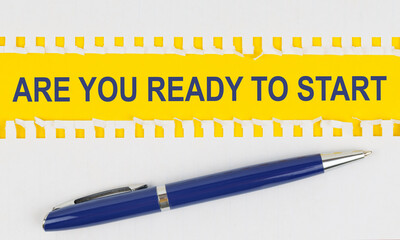 On the table are two sheets from a notebook and a pen on a yellow background written - ARE YOU READY TO START