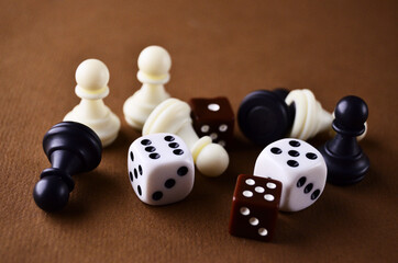 Details of the board game dice and chess pieces close-up lie on the brown table. Play board games. High quality photo