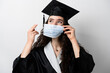 © Rabizo Anatolii - Distance learning online with medical mask at coronavirus covid-19 period. Study at home. Graduation from college. Graduate in black robe smiling. Finish university and complete master degree