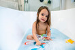 © Inti St. Clair - Happy toddler girl playing with toys in bathtub
