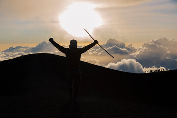 Climber celebrating at the top of the Acatenango volcano in Guatemala - hiker reaching the top at sunset - concept of effort and achievement of goals