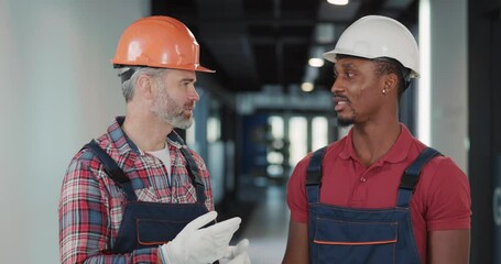 Wall Mural - Team Portrait of Successful Adult Engineer and Afro-American Electricity Worker Posing Confidently at Camera in New Building Construction. Heavy Industry People.