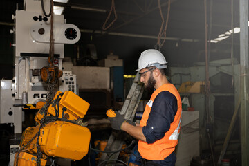 Male mechanical engineer or worker with hardhat and safety uniform checks the operation system in a factory