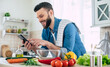 © My Ocean studio - Happy handsome bearded man is using his smart phone while he preparing vegan healthy breakfast for a lovely family