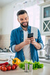 © My Ocean studio - Happy handsome bearded man is using his smart phone while he preparing vegan healthy breakfast for a lovely family