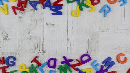 Fototapete - Word - Background - in bright colorful alphabet letters with top and bottom matching border on grey wood background viewed from overhead. Stop motion, top view, copy space