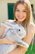 © Ivan - Beautiful young woman with bunny rabbit on farm. Portrait of young woman posing with rabbit