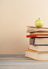 Wall Mural - Stack of colorful real books, apple on yellow background, partial view. Back to school. Copy Space. Education background.