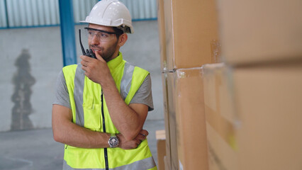 Wall Mural - Professional cargo worker talks on portable radio to contact another worker . Factory and warehouse communication concept .