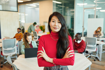 Poster - Young smiling businesswoman of Asian ethnicity crossing her arms by chest