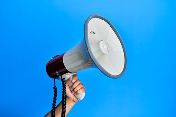 Canvas Print - Hand of hispanic man holding megaphone over isolated blue background.