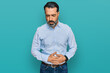 © Krakenimages.com - Middle aged man with beard wearing business shirt with hand on stomach because indigestion, painful illness feeling unwell. ache concept.