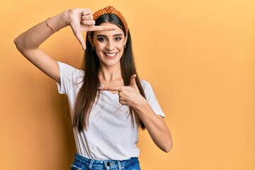 Wall Mural - Beautiful brunette young woman wearing casual white t shirt smiling making frame with hands and fingers with happy face. creativity and photography concept.