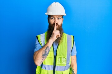 Wall Mural - Redhead man with long beard wearing safety helmet and reflective jacket asking to be quiet with finger on lips. silence and secret concept.