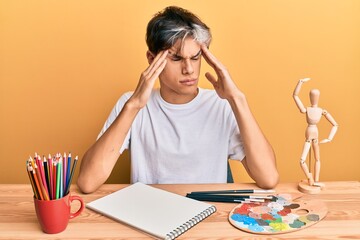 Wall Mural - Young hispanic man artist sitting at the studio with hand on head, headache because stress. suffering migraine.