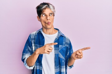 Sticker - Young hispanic man pointing with fingers to the side making fish face with mouth and squinting eyes, crazy and comical.