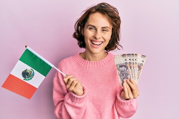 Wall Mural - Young brunette woman holding mexico flag and mexican pesos banknotes smiling and laughing hard out loud because funny crazy joke.