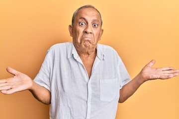 Wall Mural - Handsome mature man wearing casual white shirt clueless and confused expression with arms and hands raised. doubt concept.