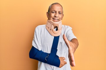 Poster - Handsome mature senior man wearing cervical collar and arm on sling smiling friendly offering handshake as greeting and welcoming. successful business.