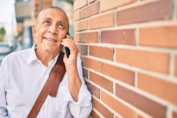 Wall Mural - senior grey-haired businessman smiling happy talking on the smartphone at the city.