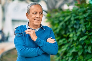 Wall Mural - senior grey-haired man with arms crossed smiling happy standing at the city.
