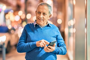 Wall Mural - senior grey-haired man smiling happy using smartphone at the city.