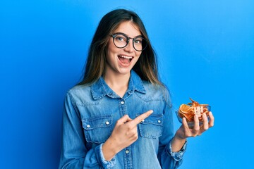 Poster - Young caucasian woman holding bowl of dry orange smiling happy pointing with hand and finger