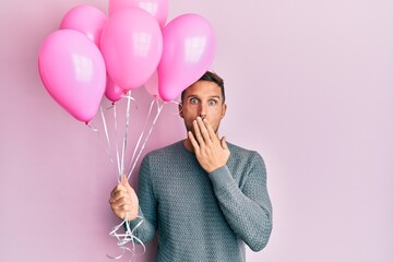 Sticker - Handsome man with beard holding pink balloons covering mouth with hand, shocked and afraid for mistake. surprised expression